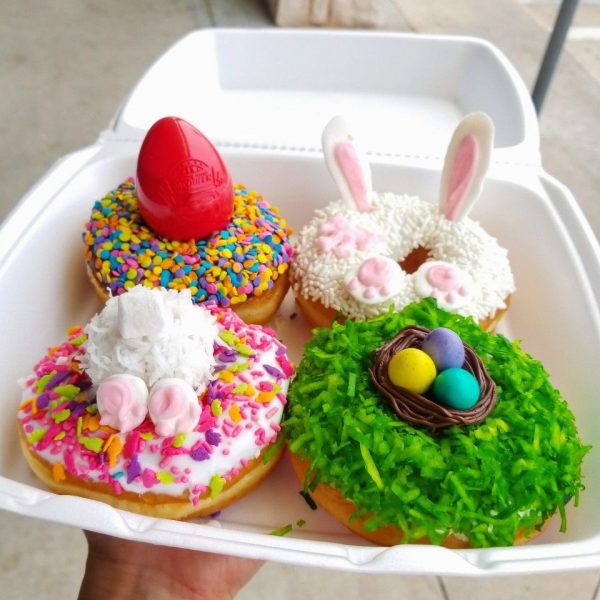 Easter donut decorated with bunny ears, pink paws, and a bow on a white sprinkle coating