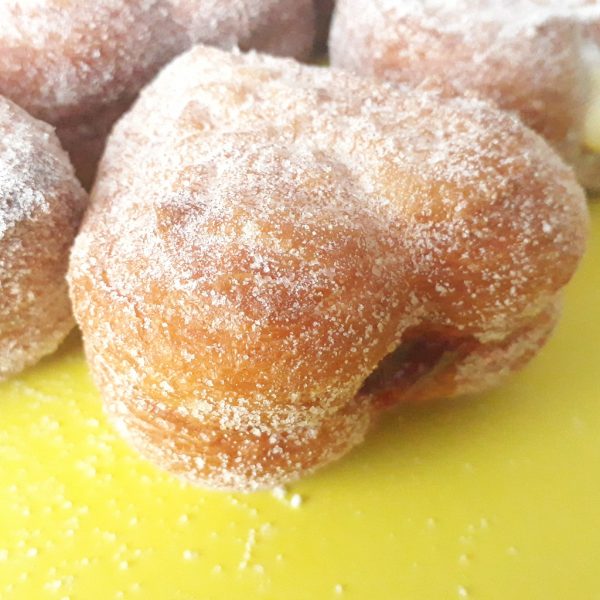 A delicious set of Mini Croissant Heart Donuts filled with Nutella, custard cream, and raspberry jelly, lightly coated with regular sugar and powdered sugar, arranged on a display tray. A perfect bite-sized indulgence for Valentine’s Day and special occasions.