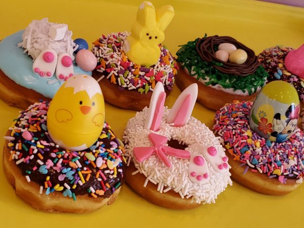 Easter donut decorated with bunny ears, pink paws, and a bow on a white sprinkle coating