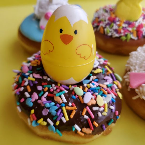 Chocolate glazed Easter donut with colorful sprinkles and a egg capsule on top