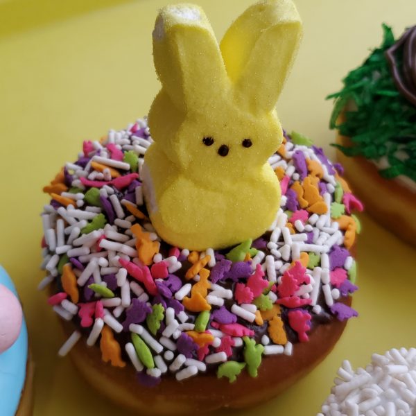 Chocolate glazed Easter donut with colorful sprinkles and a yellow Peeps marshmallow bunny on top