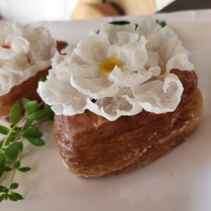Heart-shaped croissant donut filled with jam, topped with a handmade crispy white rice paper flower