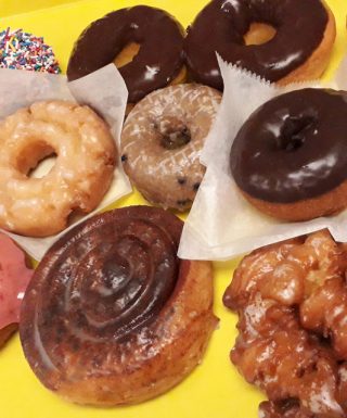 A yellow box filled with 1 Dozen Baker's Mix classic donuts from Jarams Donuts