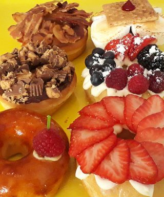 A box of twelve vibrant gourmet specialty mix donuts by Jarams Donuts.