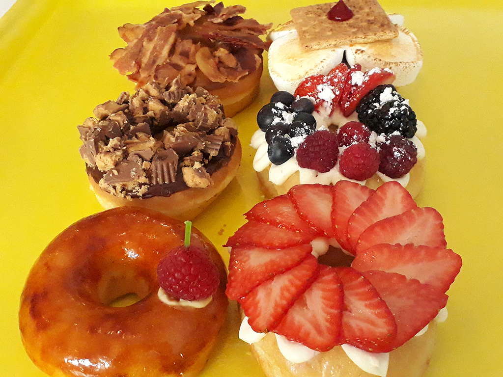 Jarams-Donuts-1-Dozen-Gourmet-Specialty-Mix A box of twelve vibrant gourmet specialty mix donuts by Jarams Donuts.
