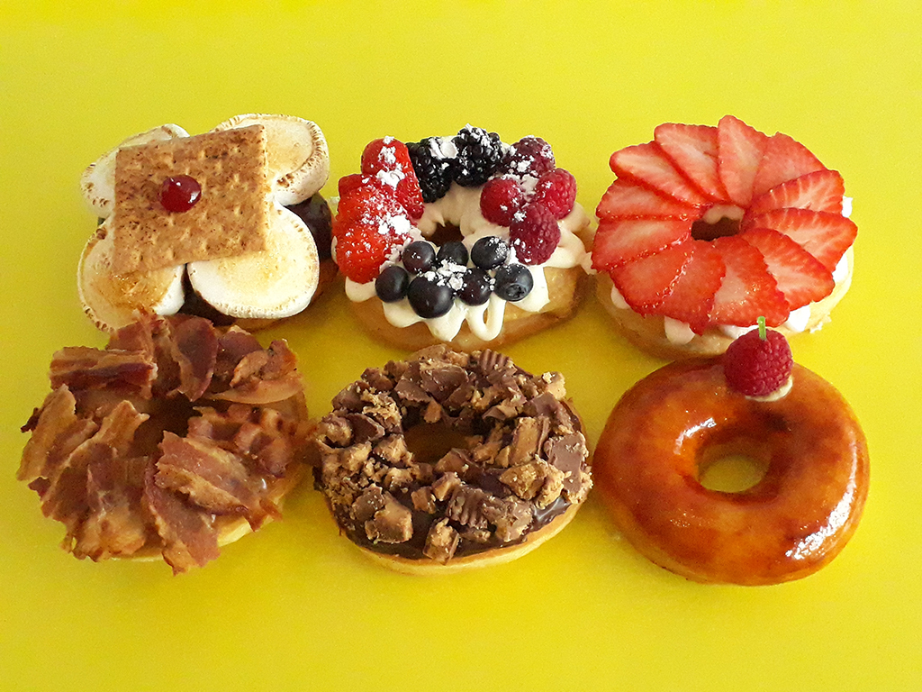 Jarams-Donuts-1-Dozen-Gourmet-Specialty-Mix A box of twelve vibrant gourmet specialty mix donuts by Jarams Donuts.